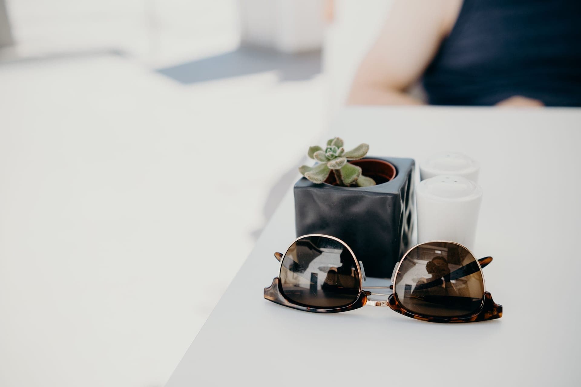 A pair of tortoiseshell acetate sunglasses resting on a warm wooden table in soft daylight