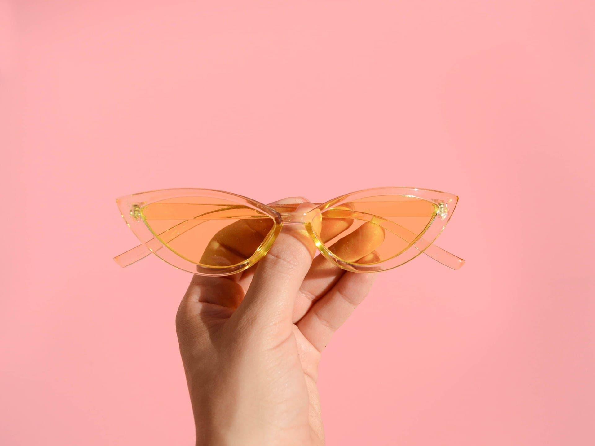 A pair of cat-eye acetate sunglasses resting on a warm neutral surface