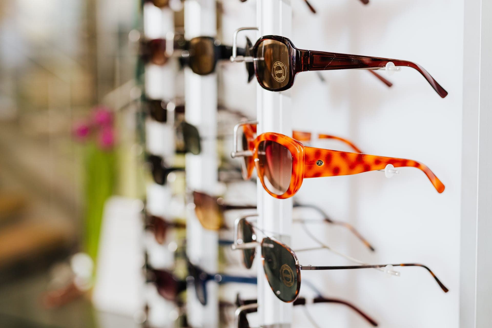 Several pairs of sunglasses arranged together on a warm neutral background
